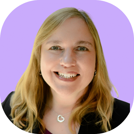 Smiling woman with long blonde hair, wearing a black top and heart-shaped necklace, poses confidently in front of a light purple background, embodying the modern style of Highline 2025.
