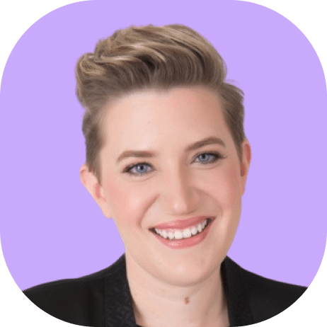 A person with short, styled blonde hair and blue eyes smiles warmly. Wearing a black jacket, they stand against a solid light purple background, embodying the confident spirit of Highline 2025.