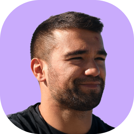 A man with short dark hair and a beard is smiling slightly, wearing a black Highline 2025 shirt, against a solid light purple background.